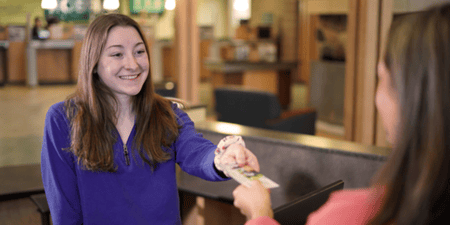 Teller helping Momentum Checking member make a deposit 